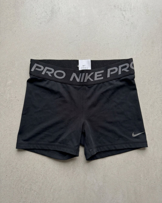Black Nike Pro compression shorts laid flat on a pale background, NIKE PRO waistband and a small swoosh at the hem.